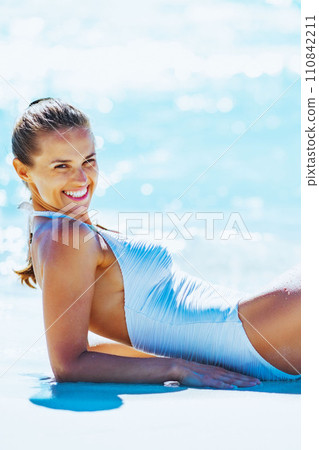 Smiling young woman laying on beach 110842211