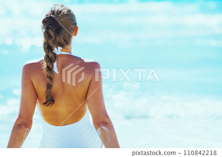 Young woman sitting at seaside. rear view 110842218