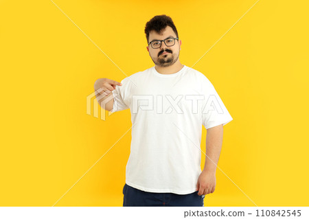 A man with a blank white t-shirt, on a yellow background. 110842545