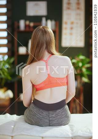 teenage girl in therapist cabinet sitting on massage table 110842839