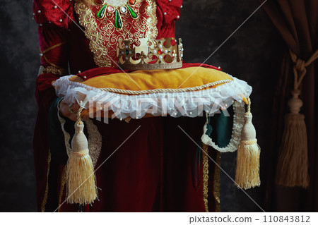 Closeup on medieval queen in red dress with crown on pillow 110843812