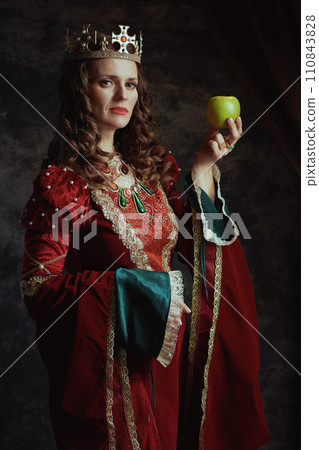 medieval queen in red dress with green apple and crown medieval queen in red dress with green apple and crown 110843828