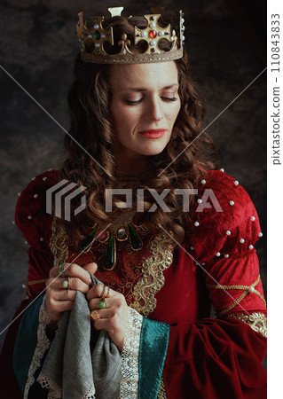 sad medieval queen in red dress with handkerchief and crown 110843833