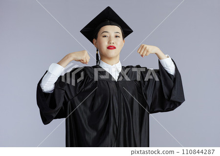 proud graduate student asian woman showing biceps against grey proud graduate student asian woman showing biceps against grey 110844287