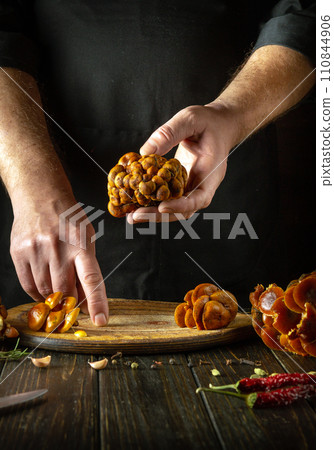 Chef hands sort fresh wild enoki mushrooms before cooking. The concept of cooking wild mushrooms Velvet shank in a restaurant kitchen 110844906
