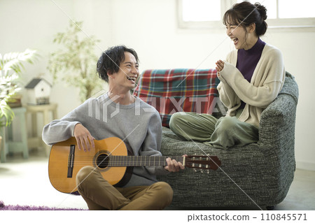 年輕夫婦坐在沙發上彈吉他唱歌 110845571