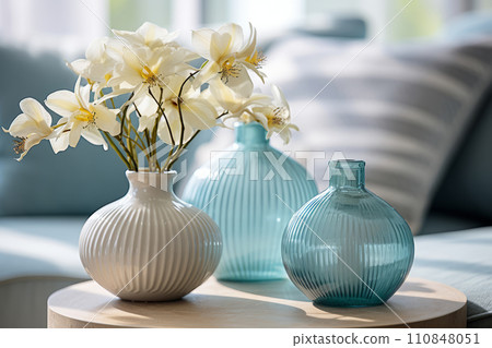 Nautical style home decor, ceramic and glass blue vases with flowers. Interior details of living room of country cottage at summer resort. Summer sunny day. 110848051