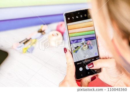 A woman takes a photo on a smartphone. Accessories for hobby embroidery knitting 110848360