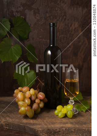 Still life with glass of white wine and grapes on vintage wooden background.. Still life with glass of white wine and grapes on vintage wooden background.. 110848874