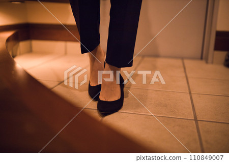 Business woman taking off pumps at the entrance Night routine 110849007