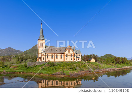 The Gothic Revival Vagan Kirke mirrors in calm Norwegian waters under Lofoten's blue sky The Gothic Revival Vagan Kirke mirrors in calm Norwegian waters under Lofoten's blue sky 110849108
