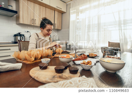 A young woman packs cupcakes in a craft. concept of food delivery. A birthday package. small business. bakery chef bakes pastries and cakes in kitchen, copy space 110849683