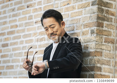 Portrait of a man in his mid-50s looking at his watch 110849699