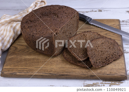 Rye Borodino (Borodinskiy) bread with a crispy crust on a wooden board, cut into slices. Homemade baking in rustic style. Selective focus, close-up. Rye Borodino (Borodinskiy) bread with a crispy crust on a wooden board, cut into slices. Homemade baking in rustic style. Selective focus, close-up. 110849921