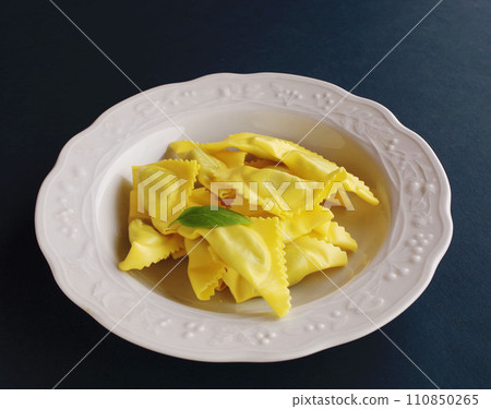 Ravioli and basil pasta dish on white plate gourmet black background Ravioli and basil pasta dish on white plate gourmet black background 110850265