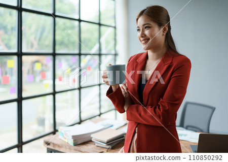 Businesswoman enjoys relaxing with a cup of coffee after a long day Businesswoman enjoys relaxing with a cup of coffee after a long day 110850292