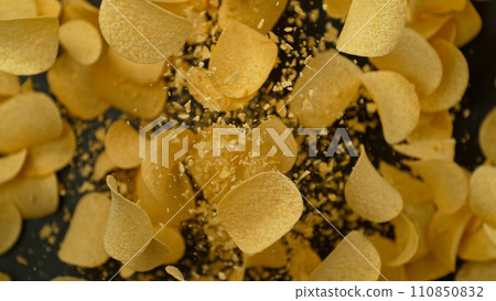 Freeze motion of flying fried potatoes chips on black background Freeze motion of flying fried potatoes chips on black background 110850832