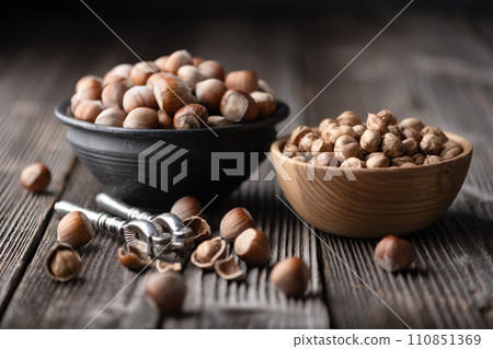 Hazelnuts being opened with a classic silver nutcracker 110851369