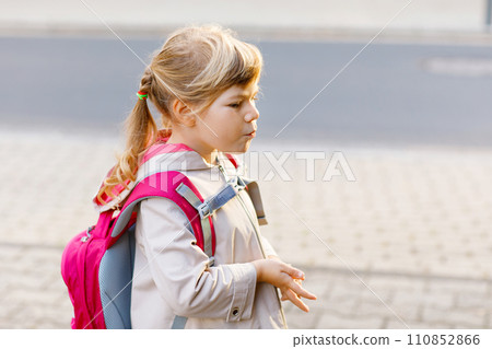 Cute little preschool girl going to playschool. Healthy toddler child walking to nursery school and kindergarten. Happy child with backpack on the city street, outdoors. 110852866