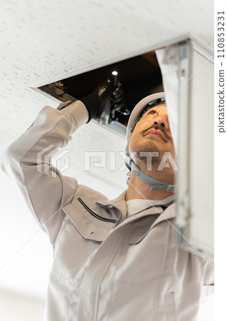 Male worker checking the ceiling inspection door Male worker checking the ceiling inspection door 110853231
