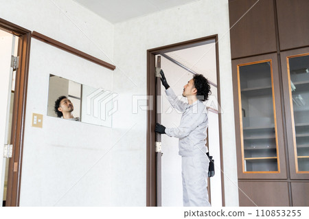 A craftsman adjusting the door hinges A craftsman adjusting the door hinges 110853255