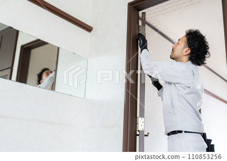 A craftsman adjusting the door hinges A craftsman adjusting the door hinges 110853256