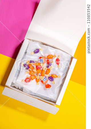 Vertical shot white empty white box with sweets candies on blue background. 110853542