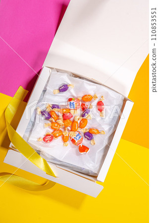 Vertical shot white empty white box with sweets candies on blue background. 110853551