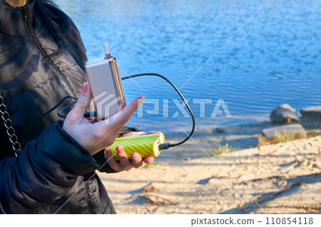 Girl's hands holding a heating device for smoking and a power bank Girl's hands holding a heating device for smoking and a power bank 110854118