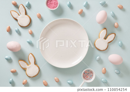 Homemade Easter bunnies shaped cookies and eggs on blue background. View from above. Festive food and snacks. Greeting card with space for text. Homemade Easter bunnies shaped cookies and eggs on blue background. View from above. Festive food and snacks. Greeting card with space for text. 110854254
