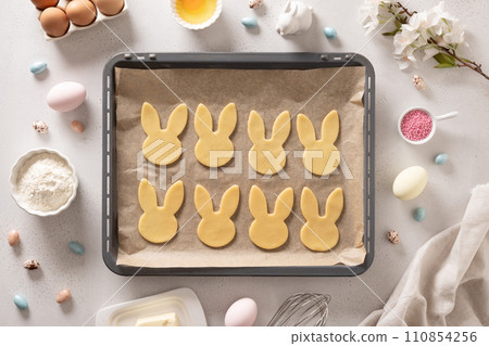 Homemade Easter bunnies shaped cookies in oven tray on white background. Top view. Space for text. Festive food and snacks. Homemade Easter bunnies shaped cookies in oven tray on white background. Top view. Space for text. Festive food and snacks. 110854256