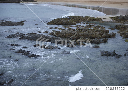 Detail of a sandy and rocky beach with calm waters. 110855222