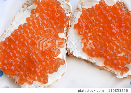 Red salmon caviar on bread and butter. A sandwich with caviar and butter on a plate. 110855256