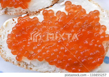 Red salmon caviar on bread and butter. A sandwich with caviar and butter on a plate. Red salmon caviar on bread and butter. A sandwich with caviar and butter on a plate. 110855257