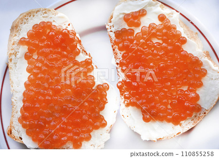 Red salmon caviar on bread and butter. A sandwich with caviar and butter on a plate. Red salmon caviar on bread and butter. A sandwich with caviar and butter on a plate. 110855258