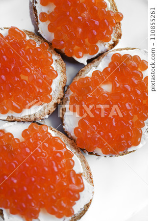 Red salmon caviar on bread and butter. A sandwich with caviar and butter on a plate. Red salmon caviar on bread and butter. A sandwich with caviar and butter on a plate. 110855261