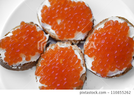 Red salmon caviar on bread and butter. A sandwich with caviar and butter on a plate. 110855262