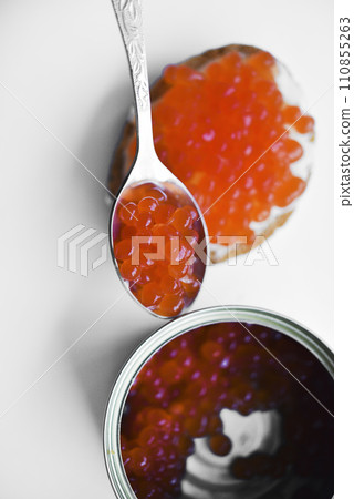 Red salmon caviar on bread and butter. A spoon with red caviar. Red salmon caviar on bread and butter. A spoon with red caviar. 110855263
