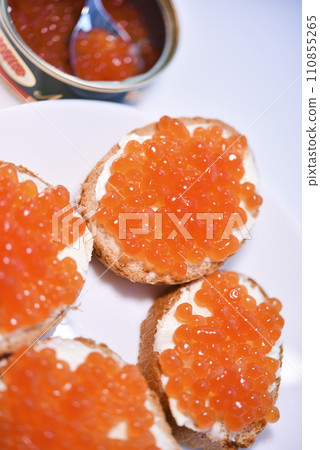 Red salmon caviar on bread and butter. A spoon with red caviar. 110855265