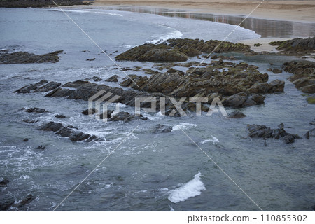 Detail of a sandy and rocky beach with calm waters. Detail of a sandy and rocky beach with calm waters. 110855302