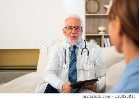 Senior man doctor examining young woman in doctor office clinic or at home. Girl patient and doctor have consultation in hospital room. Medicine healthcare medical checkup. Visit to doctor 110856815