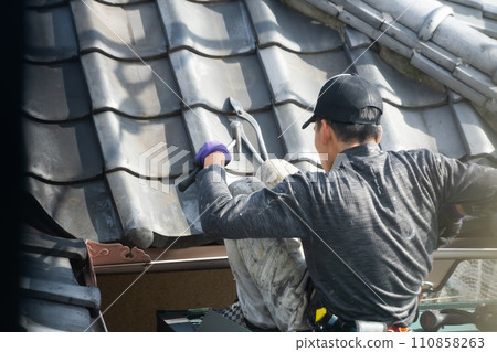 Workers repairing the roof of a detached house 110858263