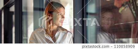Smiling woman manager standing with laptop in coworking and looking at side. Distance work concept Smiling woman manager standing with laptop in coworking and looking at side. Distance work concept 110858909