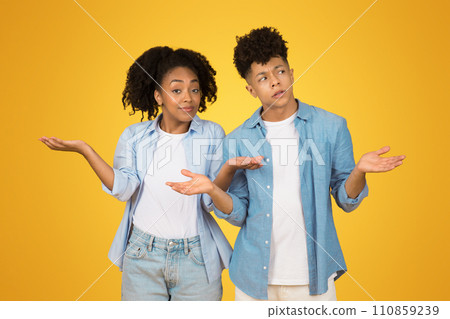 A puzzled young woman and man shrug with their hands open, showing uncertainty or lack A puzzled young woman and man shrug with their hands open, showing uncertainty or lack 110859239