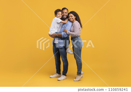 Happy Young Black Parents With Their Little Son Posing On Yellow Background Happy Young Black Parents With Their Little Son Posing On Yellow Background 110859241