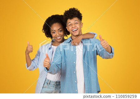 Two joyful young adults give enthusiastic thumbs up to the camera, showcasing positivity and approval Two joyful young adults give enthusiastic thumbs up to the camera, showcasing positivity and approval 110859259