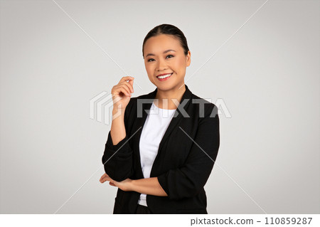 Smiling confident Asian businesswoman with one hand slightly raised in a gesture of presentation 110859287