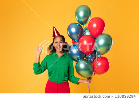 African teenager girl posing with balloons gesturing yes, yellow background 110859294