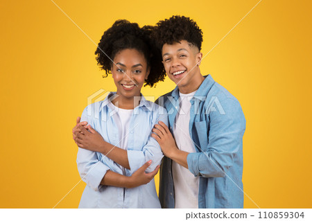Cheerful young couple in stylish denim standing back to back with bright smiles Cheerful young couple in stylish denim standing back to back with bright smiles 110859304