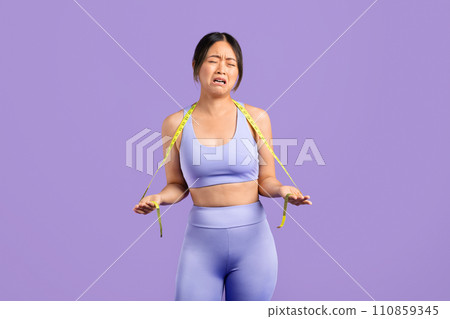 Asian woman in sportswear with measuring tape crying Asian woman in sportswear with measuring tape crying 110859345